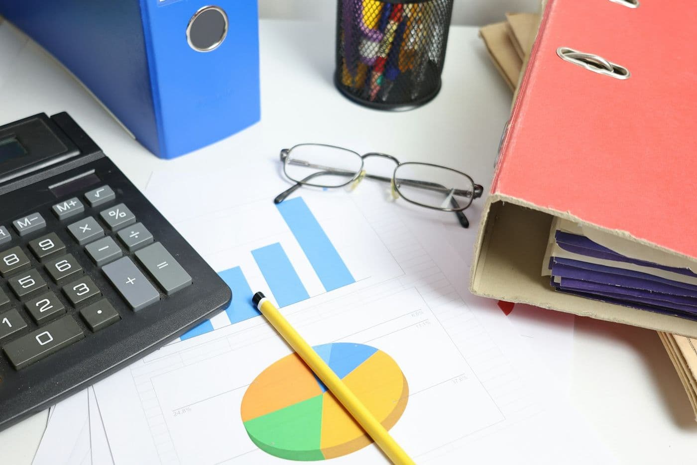 A calculator, charts and binders for bookkeeping